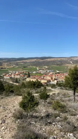Vista del pueblo de Santo Domingo de Silos rodeado de campos y montañas, captada desde una elevación cercana en el Camino de la Lana.