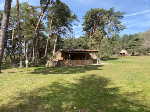 Refugio de piedra rodeado de pinos en el área recreativa de Pinarejos, ideal para un descanso en el Camino de la Lana.