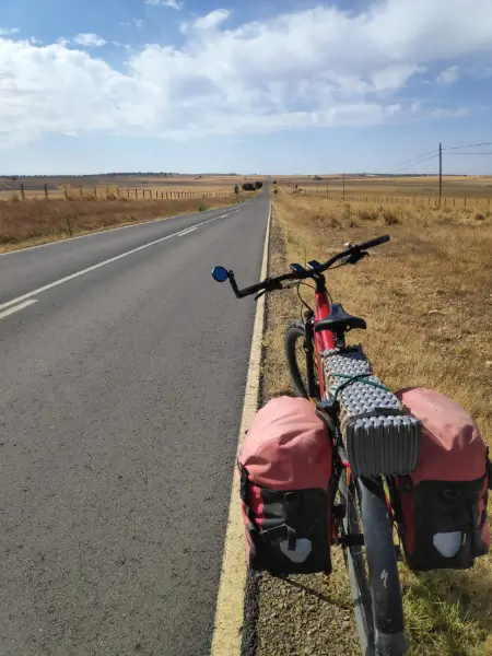 Peregrino revisando el peso de las alforjas en su bicicleta eléctrica durante el Camino de Santiago