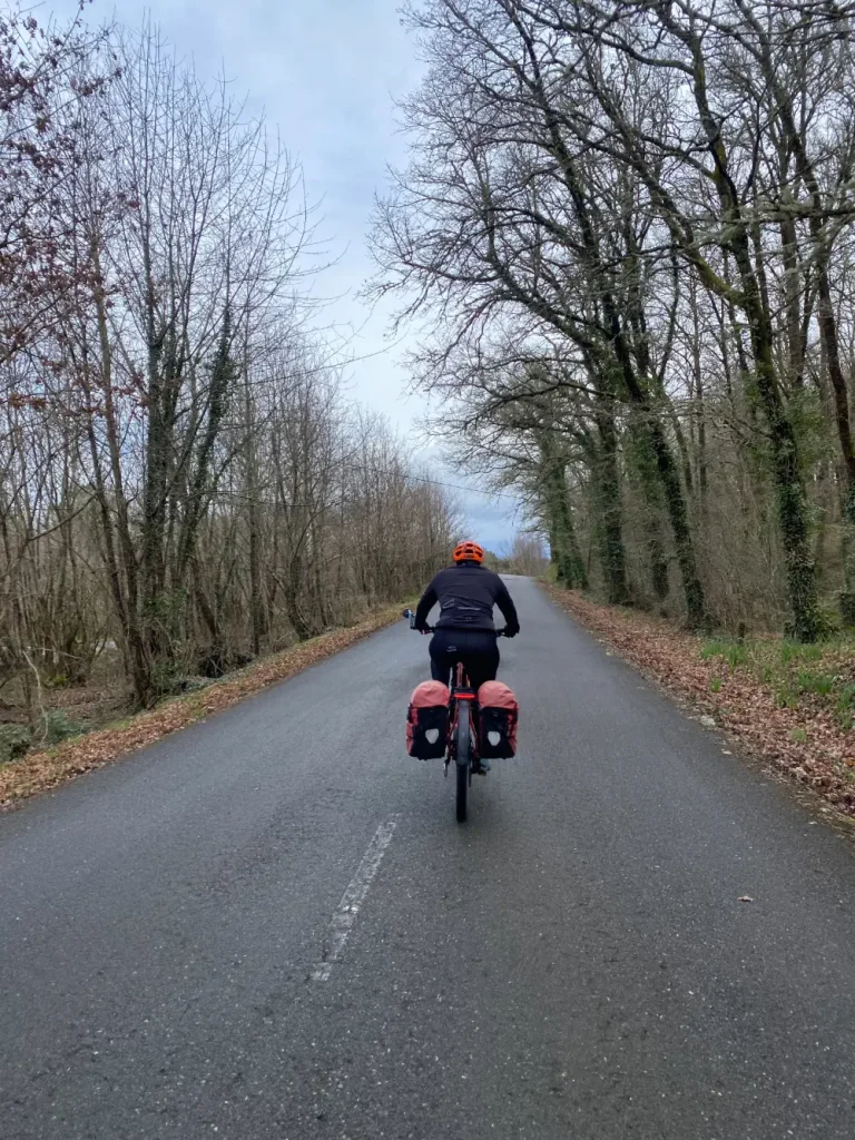 Ciclista con bicicleta eléctrica y alforjas recorriendo la Ruta en Bicicleta por la Ribeira Sacra por carretera secundaria