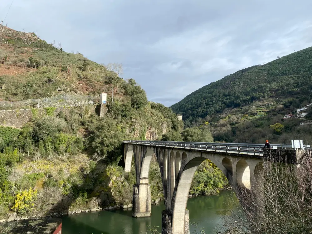 Ciclista cruzando un puente en la Ruta en Bicicleta por la Ribeira Sacra, perfecto para bicicletas eléctricas y cicloturismo
