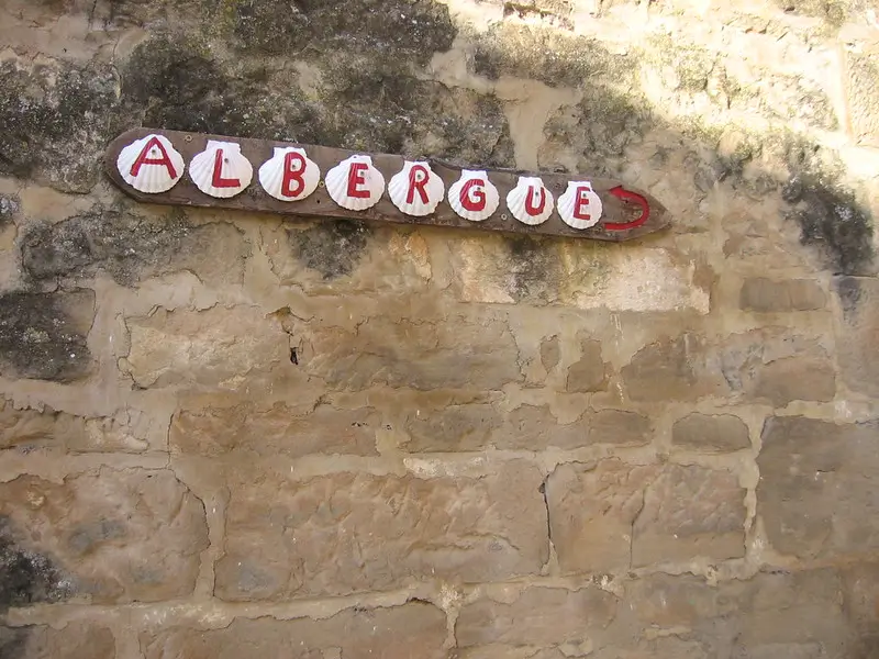 Señal artesanal que indica un albergue público para peregrinos en el Camino de Santiago