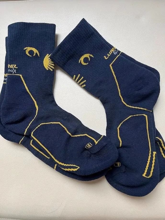 Par de calcetines Lurbel Bmax con símbolos del Camino de Santiago sobre fondo blanco