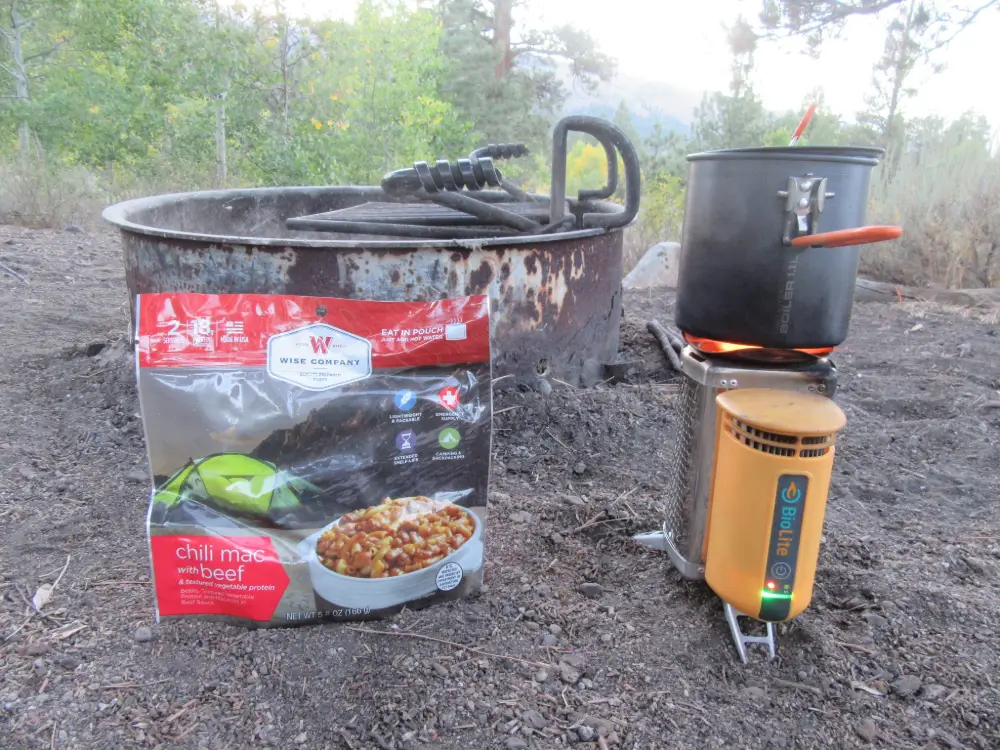 Hornillo portátil Biolite y comida deshidratada junto a una hoguera en ruta de bikepacking