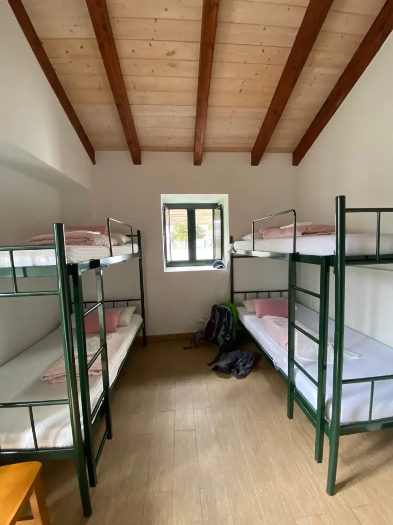 Cuarto de albergue con literas metálicas, mochilas de peregrinos y ropa tras la etapa del Camino de Santiago