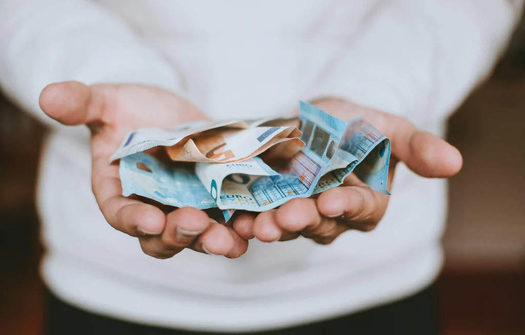 Mano de peregrino sosteniendo billetes de euro, representando el negocio en el Camino de Santiago