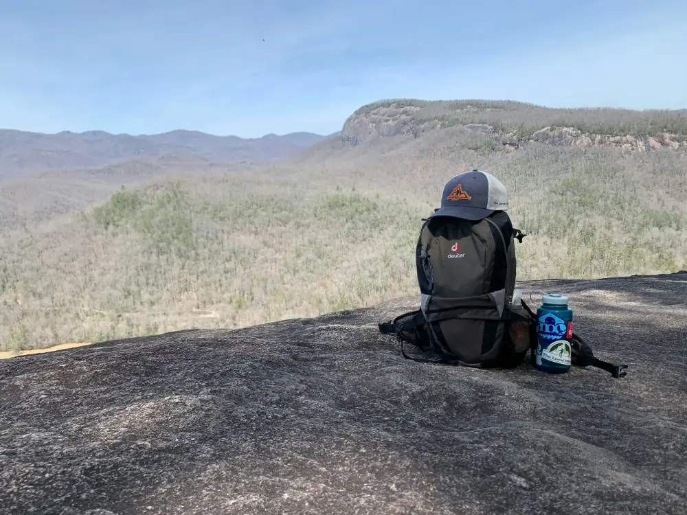 Gorra sobre mochila con paisaje montañoso al fondo, perfecta para protegerse del sol durante una jornada en el Camino