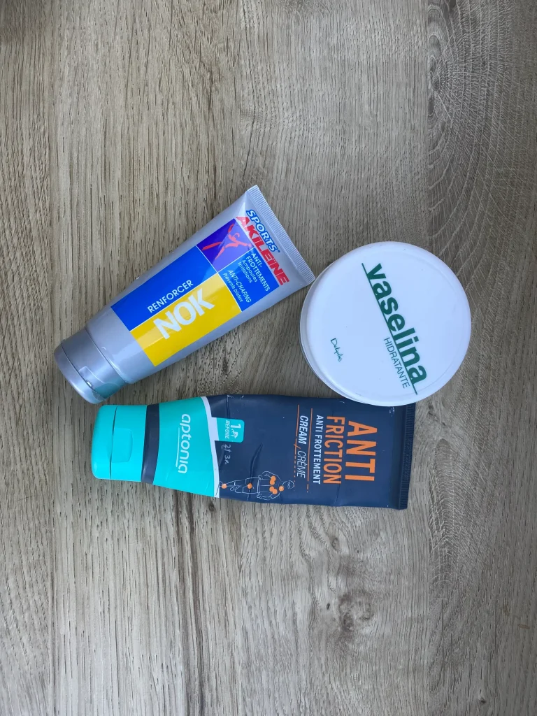 Bote abierto de vaselina junto a unas botas de senderismo y calcetines de lana para prevenir ampollas al caminar