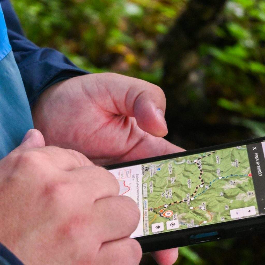 Manos sujetando un móvil con un mapa al aire libre